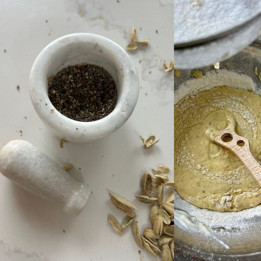 Crushed cardamom seeds in a mortar beside a bowl of yogurt cake batter with a wooden spoon.